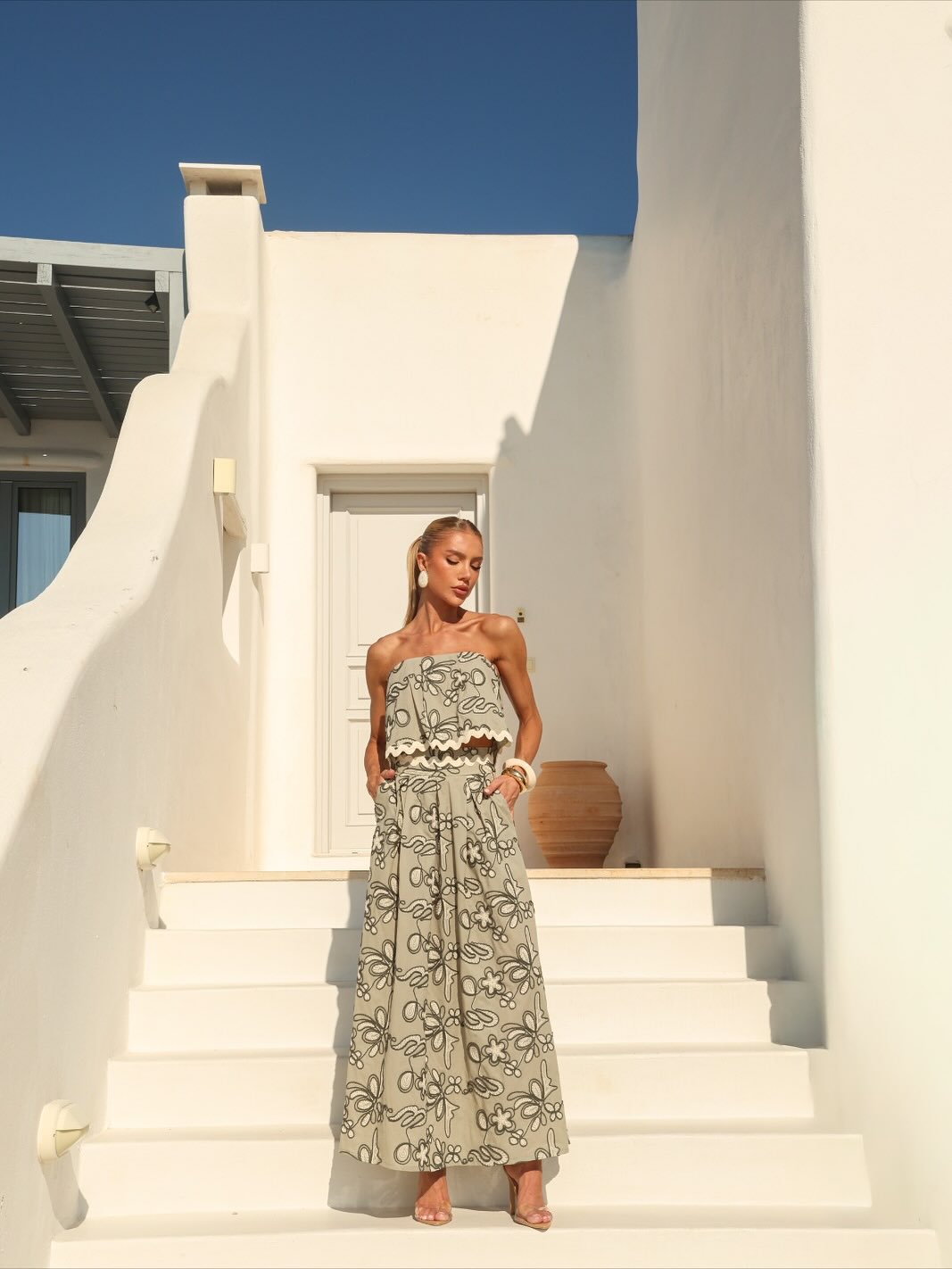Mulher usando conjunto verde-sálvia bordado em arquitetura branca